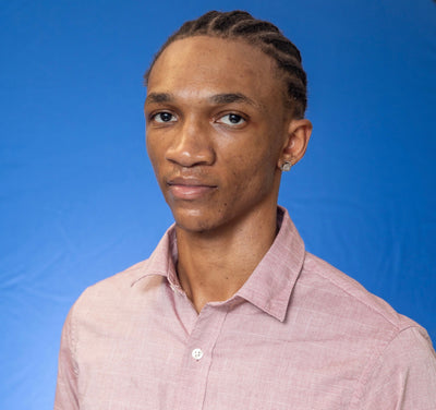 Damien Simmonds wearing a collared shirt against a blue background.